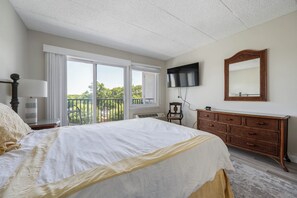 A bedroom with a bed, a dresser, a TV, and a balcony with a view. - ADORABLE AND SPACIOUS 2 BR, 2 BA CONDO ... ON REHOBOTH AVE - 18 THE ARK (Rehoboth Beach)
