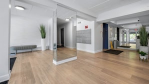 A modern interior with a wooden floor, a glass partition, a bench, potted plants, and a fire alarm on the wall. - ADORABLE AND SPACIOUS 2 BR, 2 BA CONDO ... ON REHOBOTH AVE - 18 THE ARK (Rehoboth Beach)