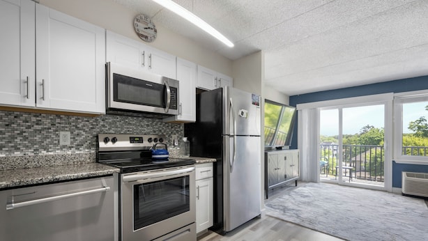 A modern kitchen with stainless steel appliances, a tiled backsplash, and a view to a balcony. - ADORABLE AND SPACIOUS 2 BR, 2 BA CONDO ... ON REHOBOTH AVE - 18 THE ARK (Rehoboth Beach)
