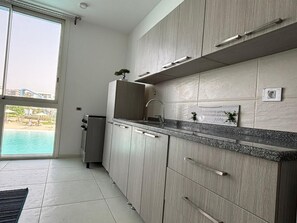A modern kitchen with light wood cabinets, a granite countertop, and a built-in oven.