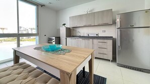 A modern kitchen with a wooden table, stainless steel appliances, and a view through large windows. - Fouka North Coast CL5-TW1-BF (Marsa Matrouh)