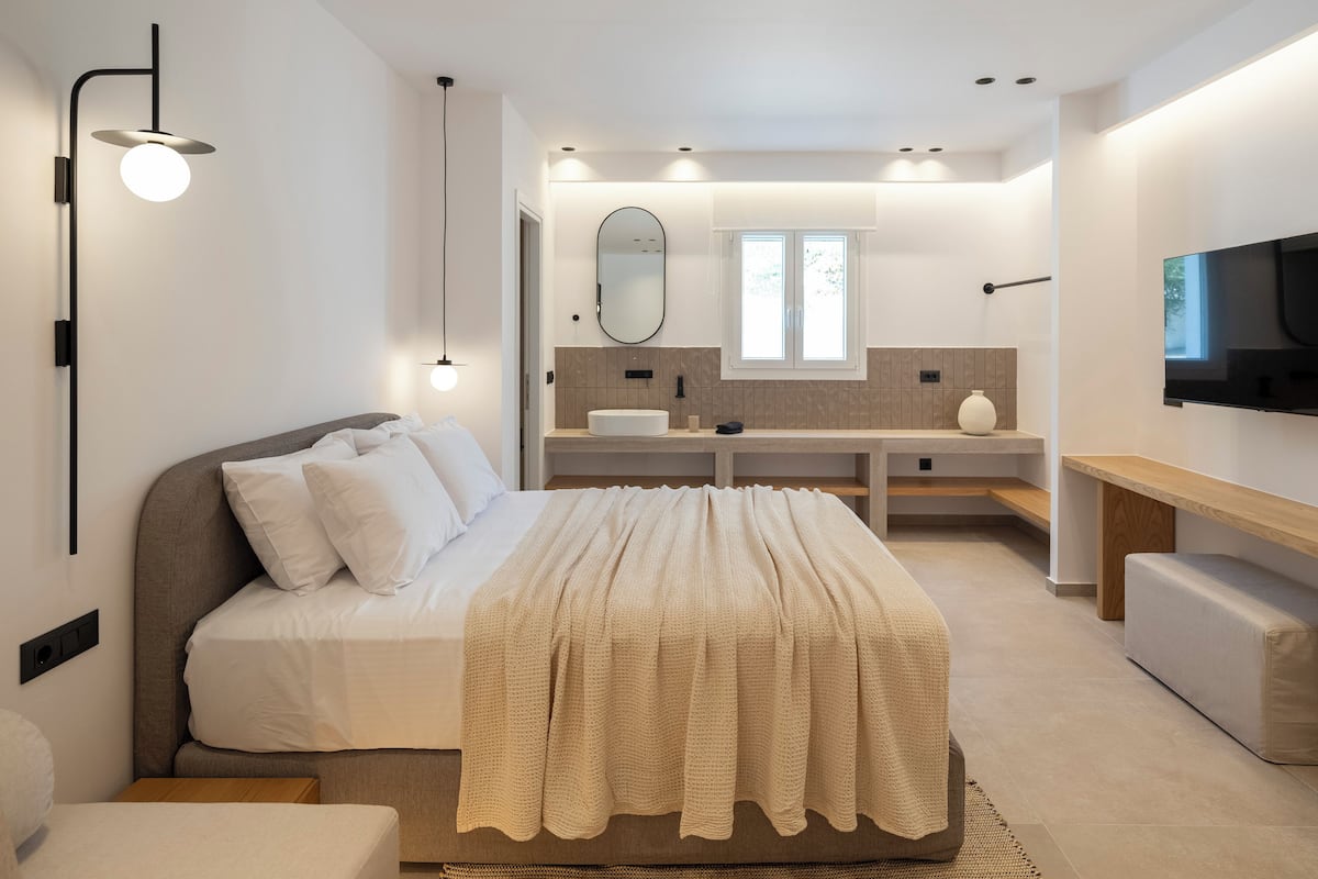 Ein modernes Schlafzimmer mit Bett, Nachttisch und einem an der Wand montierten Fernseher.