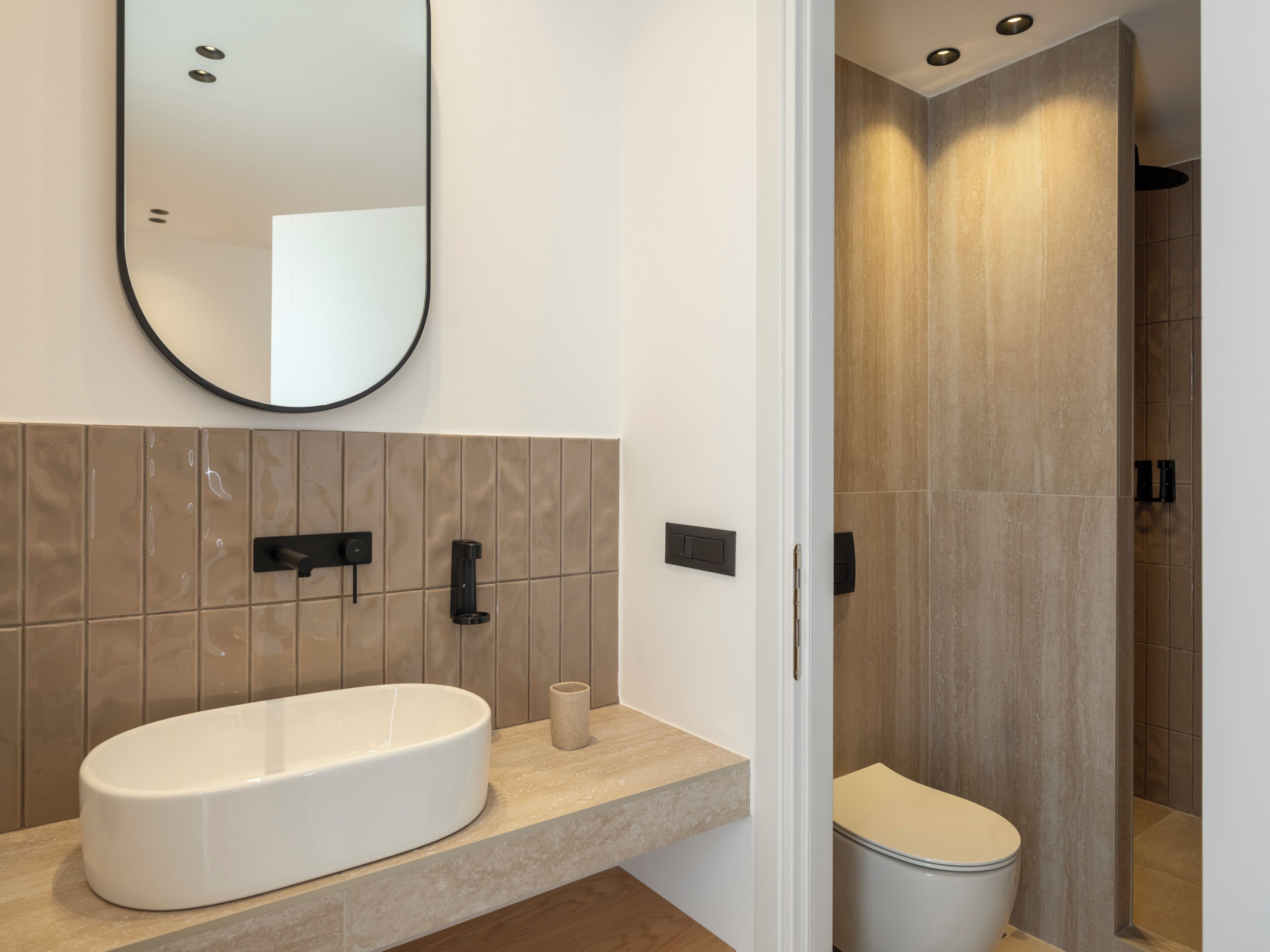 Un baño moderno con un lavamanos ovalado grande, un espejo y un inodoro.