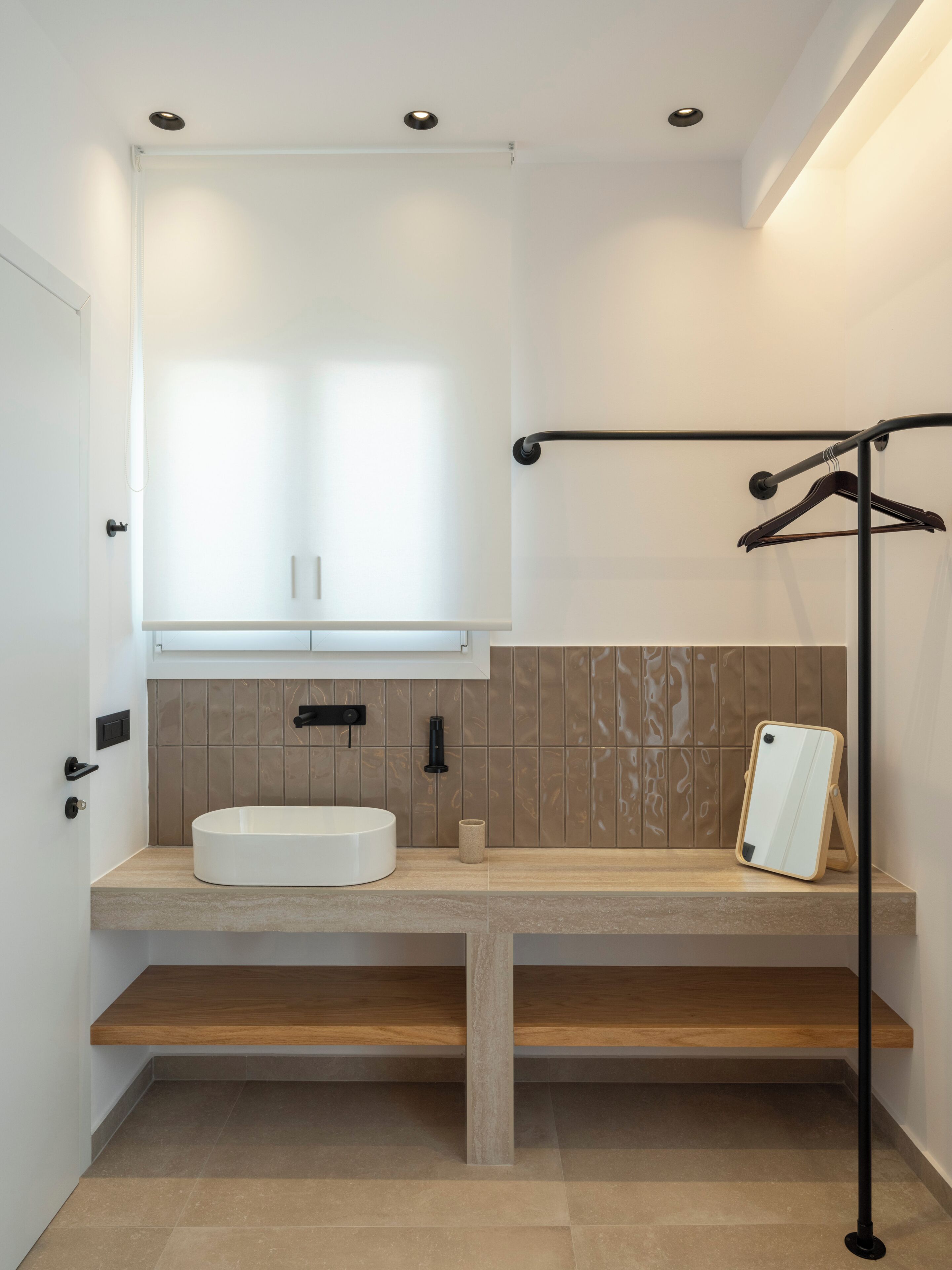 A modern bathroom with a white sink, a towel rack, and a mirror on a stand.