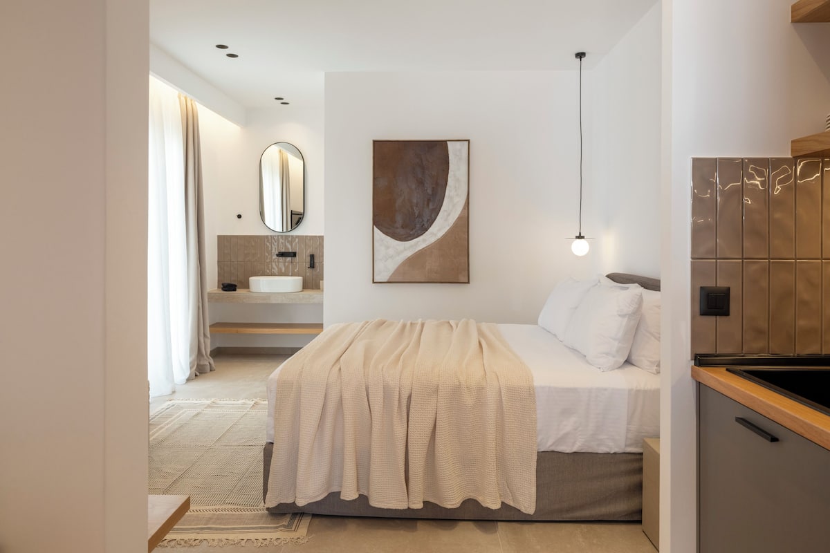 Ein modernes Schlafzimmer mit einem Bett, einem Nachttisch, einem Spiegel, einem Waschbecken und einem Bild an der Wand.