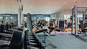 A gym with various exercise equipment, including dumbbells, weight machines, and a bench.