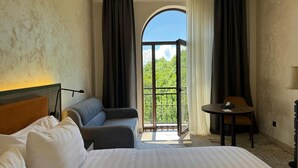A hotel room with a bed, a sofa, a table, and a balcony with a view.