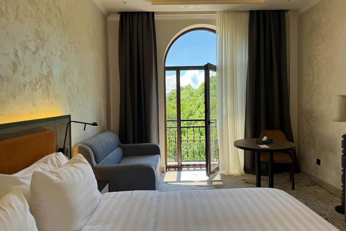 Une chambre d’hôtel avec un lit, un canapé, une table et un balcon offrant une vue.