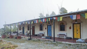 A building with multiple doors, some with windows, and a covered porch area. - The Buddha Village (Chikkaballapur)
