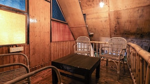 A wooden interior with a table and two wicker chairs. - The Buddha Village (Chikkaballapur)