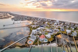 Vue aérienne d’une zone résidentielle côtière, avec des maisons, un pont et une plage.
