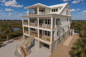 Une maison à plusieurs étages située en bord de mer, dotée de balcons, d’un escalier et d’un espace piscine.