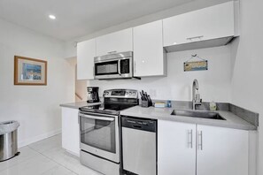 A modern kitchen with white cabinets, a stainless steel microwave, a built-in oven, and a dishwasher.