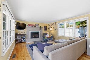 A living room with a fireplace, a sofa, a television, and a bookshelf. - 3BR with POOL, Hot Tub, 2 baths, open kitchen, pkg (Rehoboth Beach)