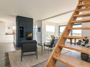 A modern interior with a stone fireplace, a wooden staircase, and a view of the outdoors. - 5 Star Holiday Home in Vejby (Vejby)
