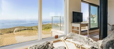 A room with a large sliding glass door leading to a balcony with a view of the sea.