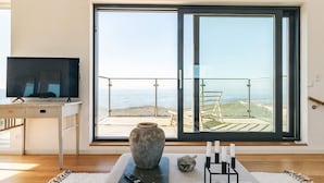 A room with a large sliding glass door, a television on a desk, a stone vase, and a candle holder. - 5 Star Holiday Home in Vejby (Vejby)