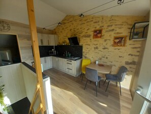 Une cuisine compacte dotée de meubles en bois, d’un four à micro-ondes et d’un coin repas comprenant deux chaises et une table.