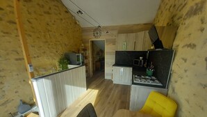 A compact kitchen with a microwave, stove, and a small dining area with a yellow chair. - 1 BEDROOM STUDIO GRILLON 2 STEPS FROM THE CENTER (Grillon)