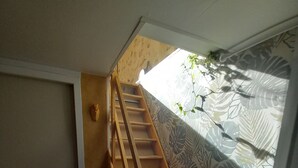 A wooden staircase leading to a loft area with a patterned curtain and a small plant. - 1 BEDROOM STUDIO GRILLON 2 STEPS FROM THE CENTER (Grillon)