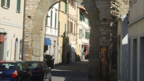 Une arche en pierre se dresse dans une ruelle bordée de bâtiments des deux côtés.