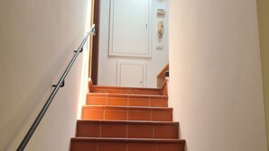 Un escalier recouvert de carreaux rouges menant à une porte blanche.