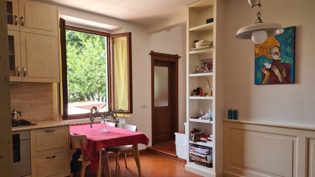 Une cuisine avec une table à manger, des chaises et une fenêtre avec des rideaux.