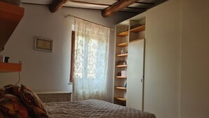 Une chambre à coucher comprenant un lit, un bureau, une fenêtre avec des rideaux et une bibliothèque intégrée.