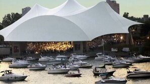 A waterfront venue with a large white tent structure, boats docked in the water, and a crowd in the background. - 2-bedroom townhome in quaint Detroit with AC and comfort (Detroit)