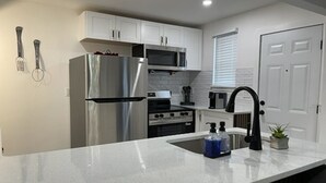 A modern kitchen with white cabinets, stainless steel appliances, and a black faucet. - 2-bedroom townhome in quaint Detroit with AC and comfort (Detroit)
