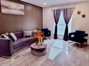 A modern living room with a curved sofa, a round coffee table, and two armchairs.