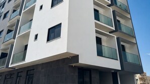 A multi-story building with balconies, large windows, and a clear sky. - Modern T2 apartment with rooftop pool (Praia)