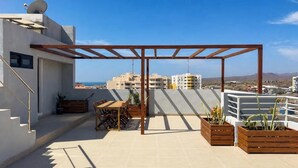 A rooftop terrace with a pergola, seating area, and planters. - Modern T2 apartment with rooftop pool (Praia)