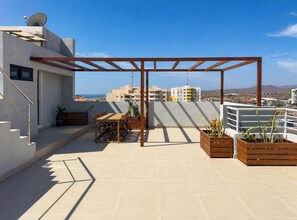 A rooftop terrace with a pergola, seating area, and planters. - Modern T2 apartment with rooftop pool (Praia)