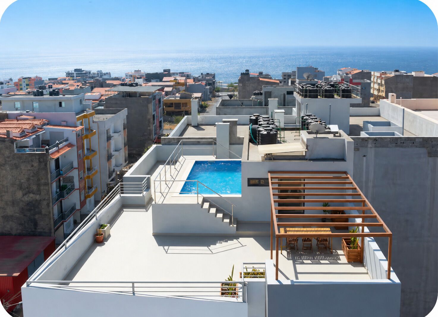 A rooftop with a swimming pool, outdoor seating, and a view of the sea.