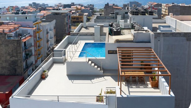 A rooftop with a swimming pool, outdoor seating, and a view of the sea. - Modern T2 apartment with rooftop pool (Praia)