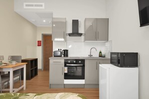 A compact kitchen with a microwave, oven, and sink. - Modern Studio Steps from Ilford Station (London)