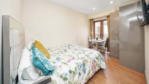 A bedroom with a bed, a desk, and a television. - Charming Studio 1 Min Walk to Ilford Station (London)