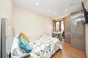 A bedroom with a bed, a desk, and a television. - Charming Studio 1 Min Walk to Ilford Station (London)