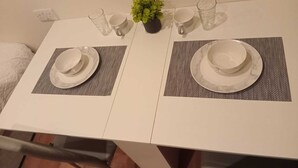 A dining table with two sets of plates, cups, and a small potted plant. - Charming Studio 1 Min Walk to Ilford Station (London)