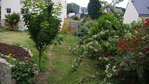 Un jardin résidentiel agrémenté d’un escalier en bois, d’un petit arbre et de divers arbustes.