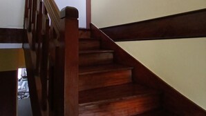 Un escalier en bois avec une rampe, une porte en haut et deux tableaux encadrés accrochés au mur.