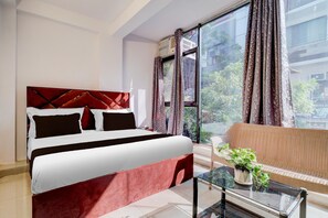 A hotel room with a bed, a sofa, a glass coffee table, and a window with curtains. - Single Room Dwarka Aakarshan Residency (New Delhi)