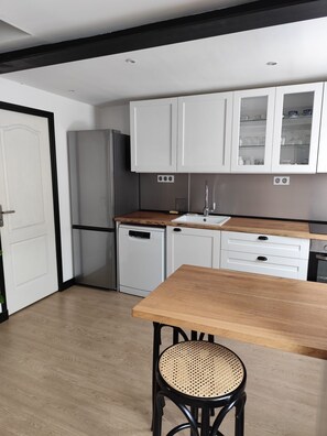 A compact kitchen with white cabinets, a wooden countertop, a sink, and a small dishwasher. - Comfortable house in the bay (Sallenelles)