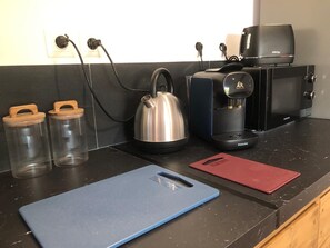 Eine Küchenarbeitsplatte mit Wasserkocher, Kaffeemaschine und zwei Glasbehältern.