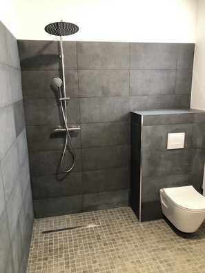 Ein modernes Badezimmer mit Dusche, Toilette und Fliesenboden.