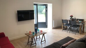 En moderne stue med et fladskærms-tv, et træspisebord med stole og en sofa.