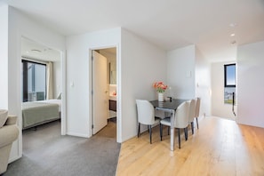Ein modernes Hotelzimmer mit Bett, einem Essbereich mit Tisch und Stühlen sowie Blick auf die Stadt.