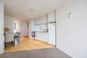 Eine moderne Küche mit weißen Schränken, einem Backofen und einem Kühlschrank.