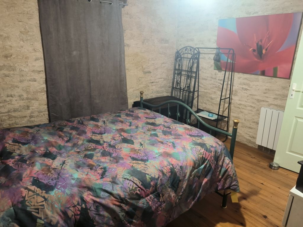 Une chambre à coucher avec un lit, une chaise en métal, un radiateur et une porte.